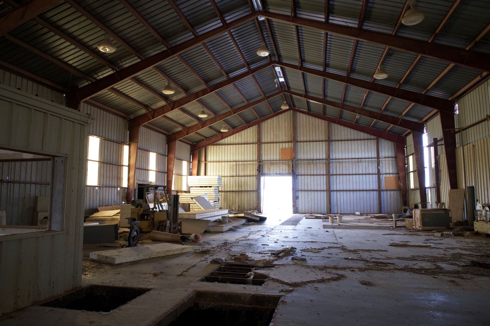 Worn, damaged concrete floor with debris and surface failure in a large garage space
